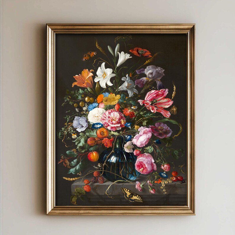 Op de afbeelding: Een ingelijst olieverfschilderij met een donker bloemstuk in een blauwe glazen vaas. Het boeket bevat witte lelies, roze rozen, oranje lelies en rode klaprozen, geaccentueerd door vlinders, kleine vruchten en korenaren op een stenen ondergrond.