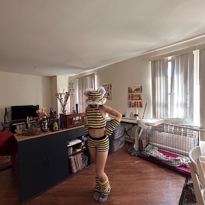 May include: A handmade crochet bee costume set, featuring a striped yellow and black halter top, shorts, arm warmers, leg warmers, and a hat with antennae. The outfit is designed to resemble a bee.