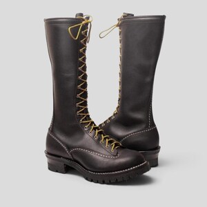 Puede incluir: Un par de botas altas de cuero negro con diseño de cordones frontales en color amarillo, ojales metálicos y una suela gruesa de goma con tacos. Las botas tienen una puntera redondeada, costuras blancas visibles en la base y caña alta.