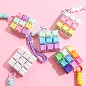 May include: Five colorful, miniature keyboard keychains with pastel-colored keycaps. Each keychain has a different color scheme, including pink, yellow, blue, green, and purple. They have a lanyard attached for easy carrying.