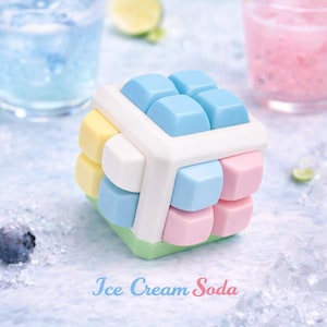 May include: A colorful cube-shaped puzzle toy with pastel-colored blocks. The toy features light blue, pink, yellow, white, and green blocks, with the text "Ice Cream Soda" in a script font.