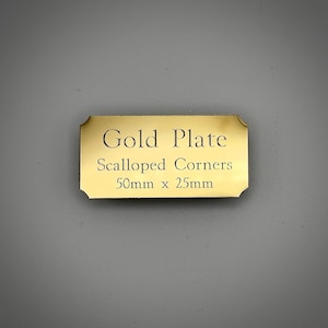 May include: A gold plate with scalloped corners, inscribed with "Gold Plate" and "Scalloped Corners". The plate measures 50mm x 25mm. The gold plate is rectangular in shape.