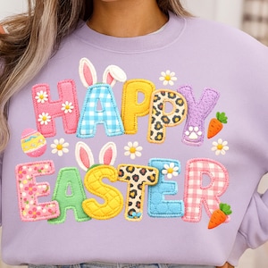 Könnte beinhalten: Ein helllila Sweatshirt mit dem Schriftzug "HAPPY EASTER" in bunten, strukturierten Buchstaben. Das Design umfasst Hasenohren, Karotten, Gänseblümchen und ein Osterei. Die Buchstaben haben Blumen-, Karo- und Leopardenmuster.