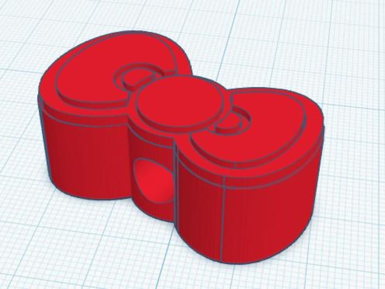 May include: A 3D-rendered red bow-shaped object. The bow has a cylindrical base with rounded edges and a circular center. The design includes layered details and a smooth, solid appearance. The object is set against a grid background.