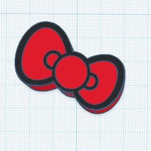 Op de afbeelding: Een rode strik met een zwarte omtrek en een rood midden. De strik is een eenvoudig, gestileerd ontwerp, waarschijnlijk voor decoratieve doeleinden. De achtergrond is een rasterpatroon.