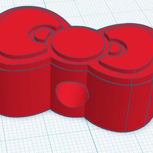 May include: A 3D-printed red bow-shaped object with a circular center and rounded edges. The bow has a layered design with a hollowed-out section on the bottom. The object is set against a grid background.