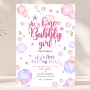 Può includere: Un invito di compleanno rettangolare decorato con bolle ad acquerello nei toni del rosa, blu e viola, con foglie verdi e piccoli fiori. Il testo recita: she's One Bubbly girl! Pop on by for Lily's First Birthday Party! 16 agosto 2026.