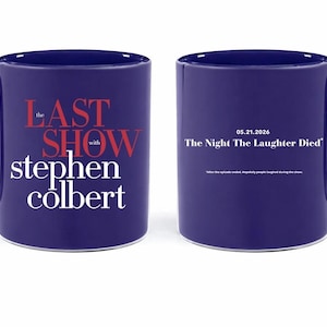 May include: A dark blue ceramic mug with a white interior and handle. The front of the mug features the text "The Last Show with Stephen Colbert" in red and white. The back of the mug has the text "05.21.2026 The Night The Laughter Died".