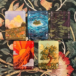 May include: Five rectangular playing cards featuring distinct illustrations: a flower field with clouds, a tropical island in blue water, a dark swamp, a sun rising over a mountain, and a tree in a field. Each card has unique symbols and letters.