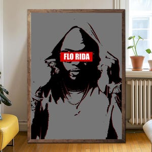 May include: A framed art print with a black and red image of a person in a hoodie. The text "FLO RIDA" is in a red rectangle across the eyes. The background is grey. The artwork is displayed in a wooden frame.