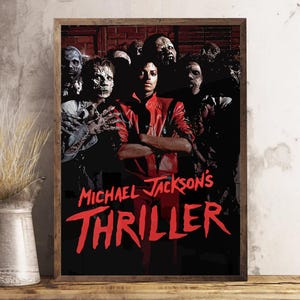 Può includere: Poster incorniciato con Michael Jackson in giacca rossa, circondato da zombi. Il titolo "Michael Jackson's Thriller" è in testo rosso su sfondo nero. Il poster è in una cornice di legno.