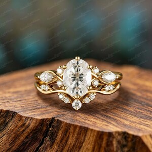 Pode incluir: Um anel de ouro com uma grande pedra central de corte oval rodeada por pedras menores de corte redondo e marquise. A banda tem um design curvo e fluido com várias pedras de destaque incrustadas ao longo da estrutura de metal.