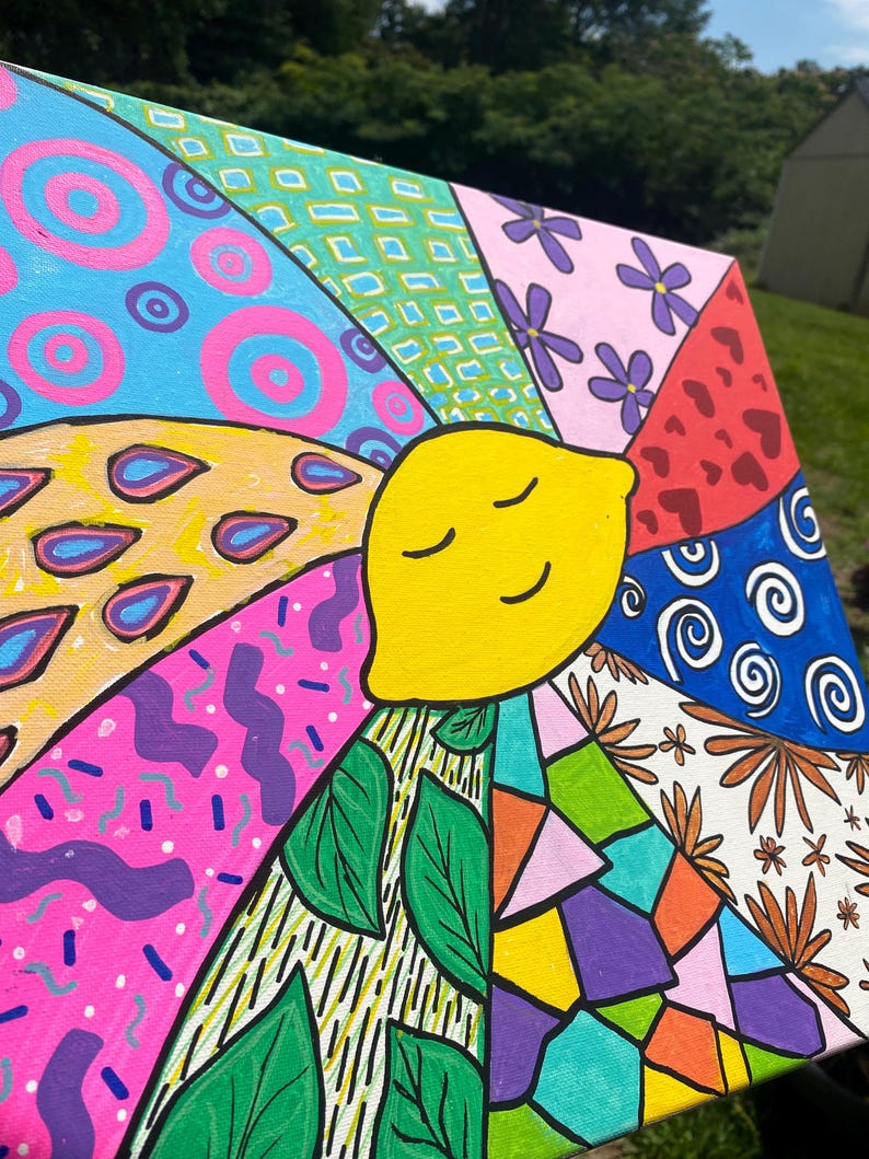 May include: A colorful canvas painting with a smiling yellow lemon in the center. The lemon is surrounded by different patterns and designs, including circles, flowers, leaves, and geometric shapes. The painting is done in a variety of bright colors, including pink, blue, green, yellow, orange, and red.