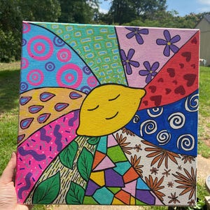 May include: A colorful abstract painting on canvas featuring a smiling yellow lemon in the center surrounded by various geometric shapes, flowers, and swirls.