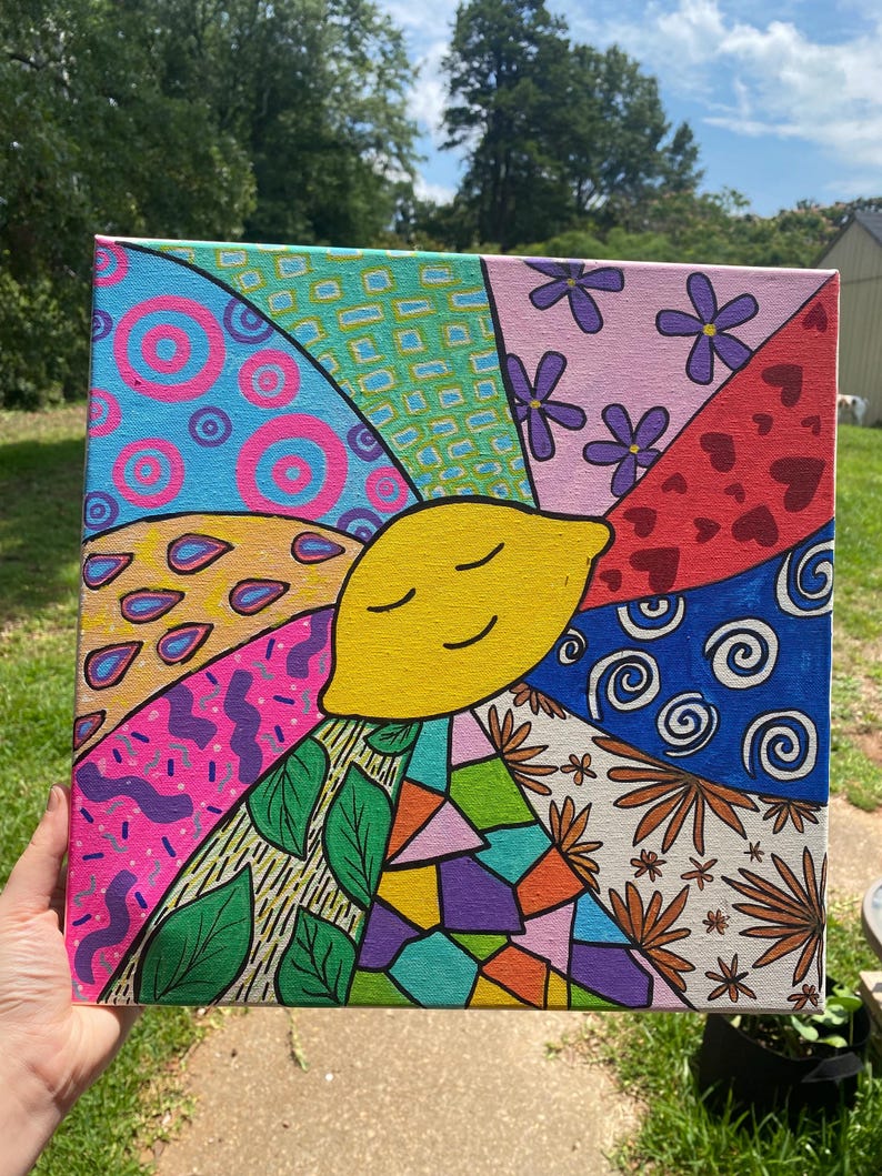 May include: A colorful abstract painting on canvas featuring a smiling yellow lemon in the center surrounded by various geometric shapes, flowers, and swirls.
