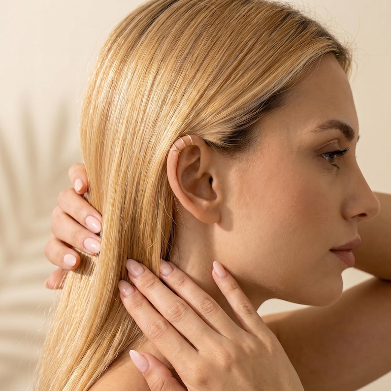 May include: A gold-toned ear cuff featuring a delicate, multi-layered wire design that wraps around the outer edge of the ear cartilage. The piece consists of several thin, parallel bands connected to form a single, cohesive, minimalist accessory.