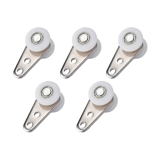 May include: Five metal and plastic roller wheels. Each wheel has a white plastic roller and a silver-colored metal bracket with two holes for mounting. The wheels are designed for smooth movement.