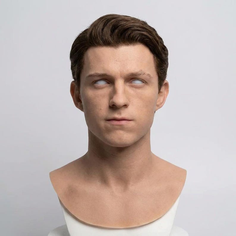 Pu&ograve; includere: Una scultura realistica di una testa umana con capelli castani corti pettinati con la riga laterale. I tratti del viso sono dettagliati con un'espressione neutra e gli occhi sono bianco solido senza pupille o iridi. Il busto &egrave; su una base.