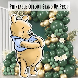 May include: A printable cutout stand-up prop featuring a cartoon bear in a blue shirt. The bear is in front of a backdrop of green and gold balloons. The text "PRINTABLE CUTOUT STAND UP PROP" is at the top of the image.