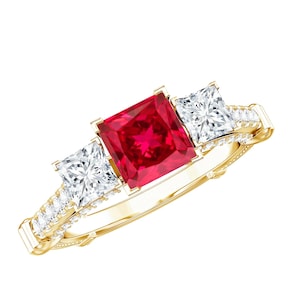 May include: A yellow gold ring featuring a large square-cut red gemstone at the center, flanked by two smaller square-cut clear gemstones. The band is decorated with a row of tiny clear stones along each side, set in a polished gold metal frame.