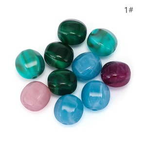 Könnte beinhalten: Eine Ansammlung von zehn glatten, runden Perlen mit marmorierten Mustern in verschiedenen Farben, darunter Dunkelgrün, Hellgrün, Türkis, Blau, Rosa und Violett. Jede Perle hat eine glänzende Oberfläche und ein Loch. Der Text 1# ist sichtbar.