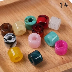 May include: A selection of brightly coloured, cylindrical beads in shades of brown, yellow, teal, red, pink, and white. The beads are displayed on a wooden tray. The number "1#" is visible in the top right corner.