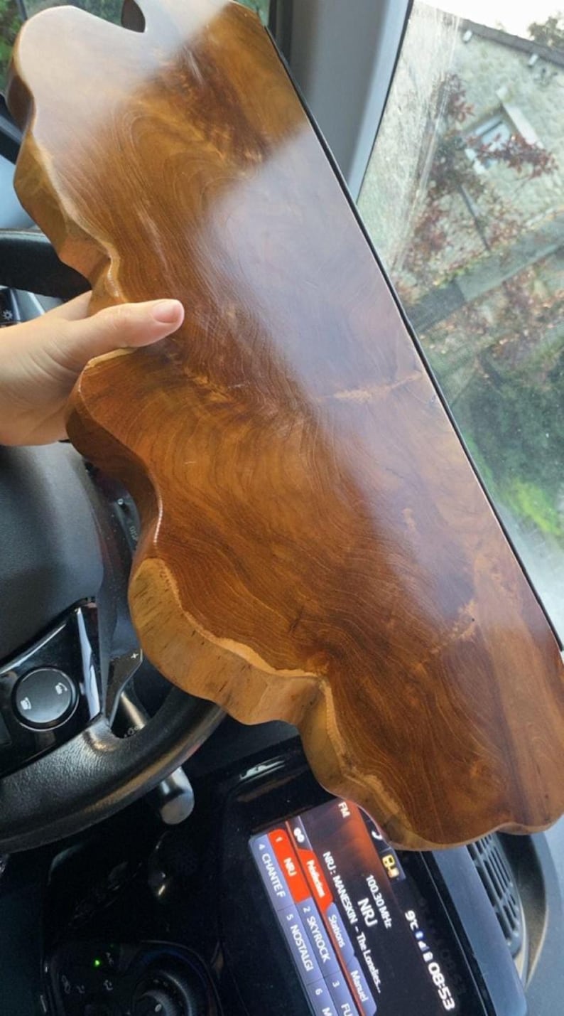 Pode incluir: Uma t&aacute;bua de madeira de bordo natural, polida, com uma forma irregular e um acabamento liso e brilhante. A madeira apresenta uma cor castanha quente e rica com padr&otilde;es de veios vis&iacute;veis e bordos org&acirc;nicos ondulados na lateral.
