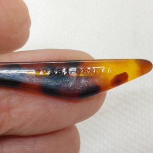 May include: Close-up of a tortoiseshell-patterned eyeglass arm. The arm is a mix of brown, black, and amber colors. The text "120/50/140" is printed on the arm.