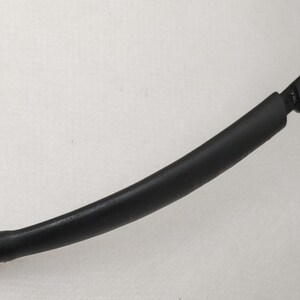 May include: A black eyeglass arm with a curved design. The arm is made of a smooth, matte material and has a rounded tip. The arm is connected to a hinge.