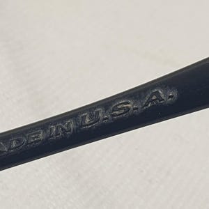 Puede incluir: Primer plano de un objeto negro con el texto "MADE IN U.S.A." grabado en la superficie. El objeto parece ser parte de un art&iacute;culo m&aacute;s grande, posiblemente una herramienta o accesorio.