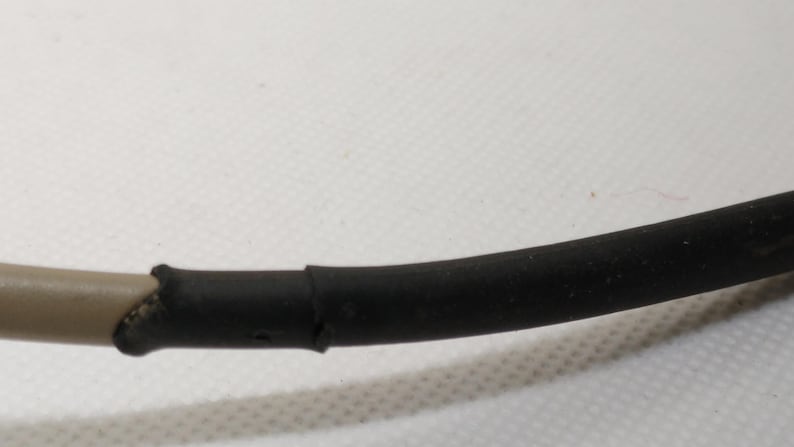 Puede incluir: Primer plano de un cable negro y marr&oacute;n. El cable est&aacute; curvado y parece estar hecho de goma o un material similar. La secci&oacute;n negra es m&aacute;s gruesa que la secci&oacute;n marr&oacute;n, y las dos secciones est&aacute;n unidas.
