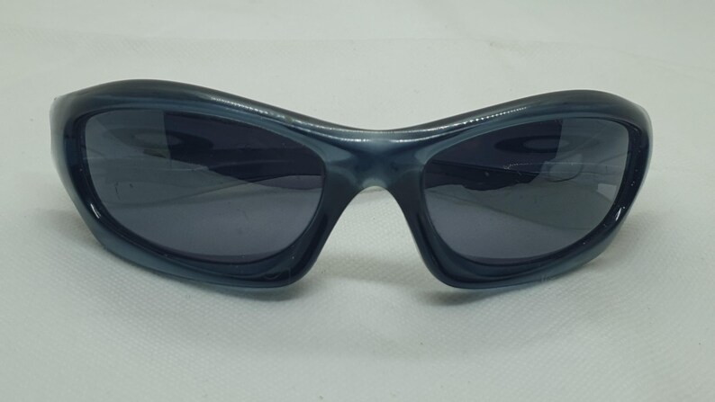 May include: Dark blue sunglasses with a curved, wraparound design. The lenses are a darker shade of blue, providing a sleek and modern look. These sunglasses offer a sporty aesthetic.