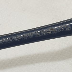 Puede incluir: Primer plano de un objeto met&aacute;lico azul oscuro con el texto "MADE IN U.S.A." grabado en la superficie. El texto est&aacute; en may&uacute;sculas y parece ligeramente desgastado.
