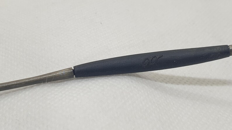 May include: Close-up of a black eyeglass arm with a silver-colored metal frame. The black portion has a subtle, curved design and the letters "00" are printed on the black portion.