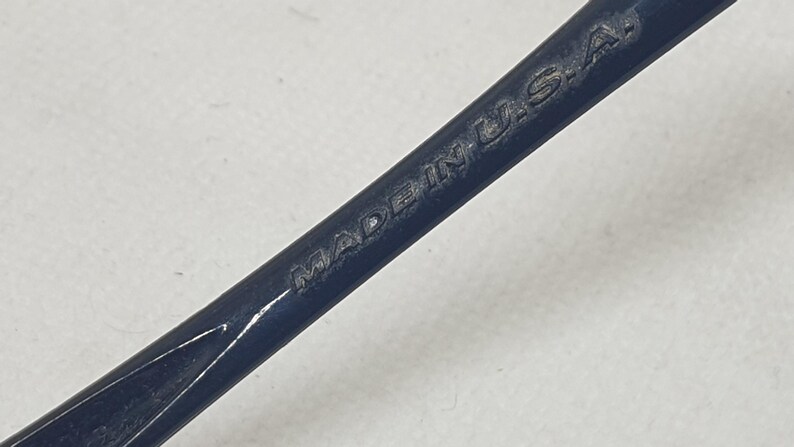 Puede incluir: Primer plano de una herramienta de metal azul oscuro con las palabras "MADE IN U.S.A." grabadas en la superficie. La herramienta tiene una forma curva y parece ser un instrumento especializado.