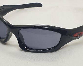 Oakley Monster Dog Schwarzer Rahmen mit roten Logos. Hergestellt in den USA