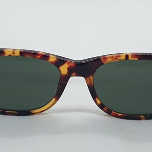Puede incluir: Gafas de sol con montura cl&aacute;sica de carey y lentes verde oscuro. Las gafas de sol tienen forma rectangular con bordes redondeados. La montura presenta una mezcla de tonos marrones, negros y amarillos.