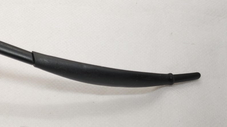 May include: A curved, black rubber component with a cylindrical end. The object appears to be a part of a larger mechanism or device, possibly a hose or a handle. The surface is smooth and matte.