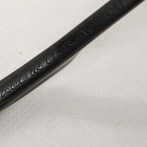 May include: Close-up of a black tool with the words "MADE IN U.S.A." embossed on its surface. The tool appears to be made of a durable material and is angled diagonally across the frame.