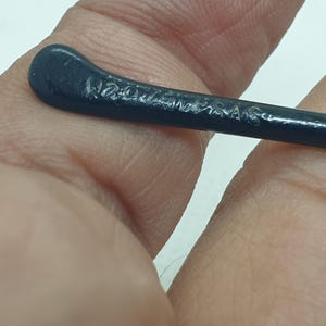 Puede incluir: Primer plano de una patilla de gafas azul oscuro. El texto "W2020MAS" est&aacute; grabado en la patilla. La patilla es curva y parece estar hecha de un material liso, posiblemente pl&aacute;stico.