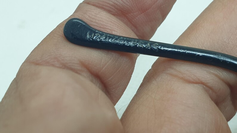 Puede incluir: Primer plano de una patilla de gafas azul oscuro. El texto "W2020MAS" est&aacute; grabado en la patilla. La patilla es curva y parece estar hecha de un material liso, posiblemente pl&aacute;stico.