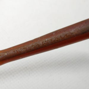 Puede incluir: Primer plano de un objeto marr&oacute;n con la inscripci&oacute;n "MADE IN U.S.A." impresa. El objeto parece estar hecho de un material marr&oacute;n oscuro, posiblemente madera o una sustancia similar. El objeto est&aacute; sobre un fondo blanco.