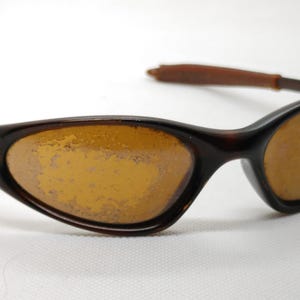 Puede incluir: Gafas de sol marrones con lentes de color &aacute;mbar. Las monturas son de color marr&oacute;n oscuro, con un patr&oacute;n de carey. Las patillas son de color marr&oacute;n claro. Las lentes tienen un ligero tono amarillo.