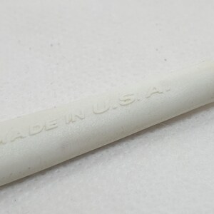 K&ouml;nnte beinhalten: Nahaufnahme eines wei&szlig;en Objekts mit dem gepr&auml;gten Text "MADE IN U.S.A.". Das Objekt hat eine zylindrische Form mit einem silberfarbenen Ende. Der Hintergrund ist eine schlichte wei&szlig;e Oberfl&auml;che.