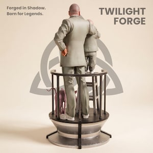 Pu&ograve; includere: Una scultura con due figure in abiti grigi in piedi su una piattaforma circolare con un cane. La piattaforma ha una ringhiera nera e una base argentata. Il testo "TWILIGHT FORGE" &egrave; visibile.