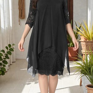Puede incluir: Vestido negro con dise&ntilde;o en capas. El vestido presenta un corpi&ntilde;o y mangas de encaje, con una superposici&oacute;n fluida y transparente. El dobladillo llega justo por debajo de la rodilla. Adecuado para ocasiones formales.