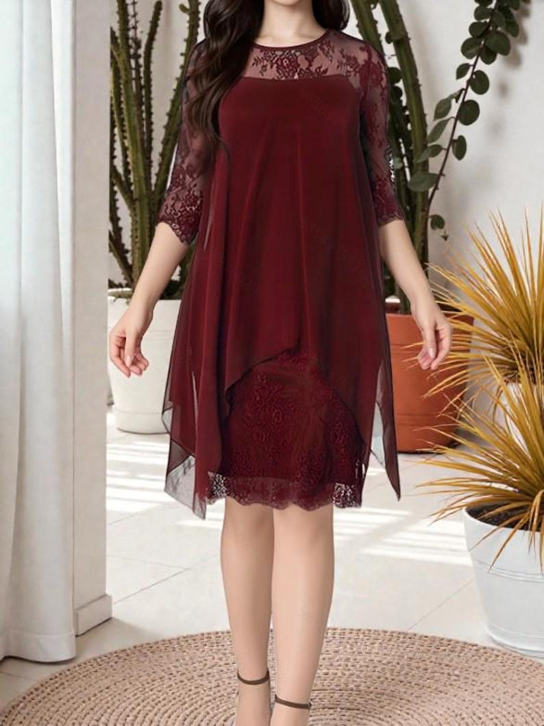 Puede incluir: Vestido burdeos con dise&ntilde;o en capas. El vestido presenta un corpi&ntilde;o y mangas de encaje, con una superposici&oacute;n transparente. El dobladillo es asim&eacute;trico y el vestido llega a la rodilla. El vestido se usa con tacones negros.