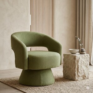 May include: A green swivel chair with a rounded back and armrests. The chair sits on a pedestal base. Beside the chair is a stone side table with a small white bowl and decorative stones.