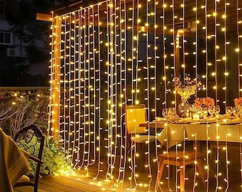 May include: An outdoor setting at night, lit by a cascade of warm, golden string lights. The lights are suspended from a wooden frame, creating a welcoming atmosphere. A table set for a meal is visible in the background, adding to the festive feel.