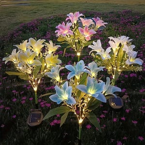 May include: Solar-powered lily flower lights in various colors, including pink, white, yellow, and blue. Each flower has a green stem and leaves, with small LED lights. The lights are set in a garden with purple flowers.